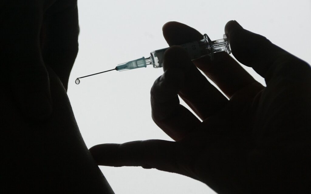 A doctor's hand holds an injection shortly before a vaccination. ©Keystone/DPA